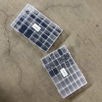 Two clear grid boxes holding black nickel LH Stinger fastener kit screws, washers, nuts, T-nuts, inserts, and shims.