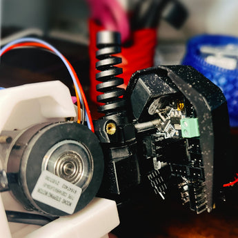 CB-C2 V2 black printed EBB36 CAN board cover mounted on a Voron Clockwork 2 toolhead with cable gland and cooling fan visible