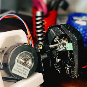 CB-C2 V2 black printed EBB36 CAN board cover mounted on a Voron Clockwork 2 toolhead with cable gland and cooling fan visible